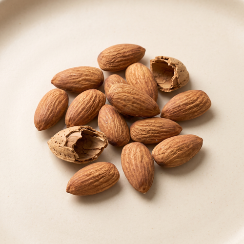 a small naturally scattered handful of raw almonds, two cracked shells alongside