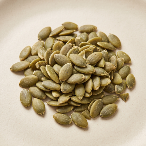 a small loose pile of natural green shelled pumpkin seeds