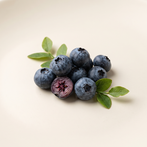 a cluster of tiny wild bilberries with dark blue dusty bloom, a sliced berry showing purple flesh, and a few green leaves